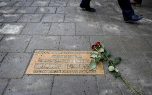 Pedestrians walk past a plaque marking the location where Swedish Prime Minister Olof Palme was killed 25 years ago in Stockholm