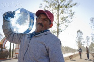 Mexican worker carrying large water bottle.