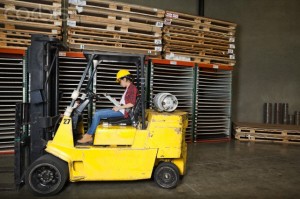 Asian female industrial worker looking at clipboard while sitting in a forklift truck