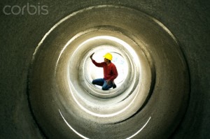 Construction worker wearing hard hat inspecting pipe
