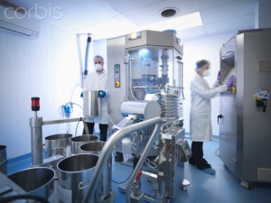 Workers with tablet pressing machine in pharmaceutical factory