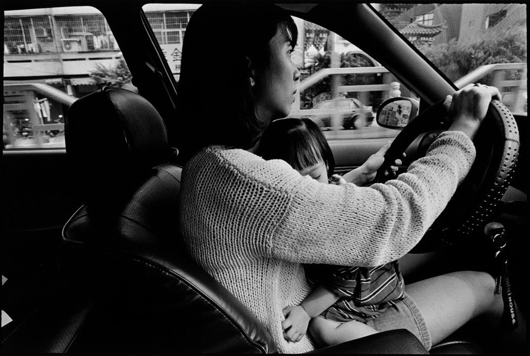 TAIWAN. Taipei. 1998. In order to pacify her daughter, a mother lets her child sit on her lap on their way home, neglecting traffic safety and regulations.