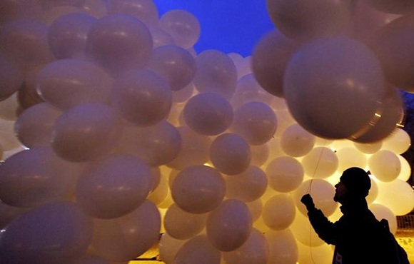 A crew member carries balloons to a site during preparations for the shooting of an advertisement promoting a Czech beer in the central Prague's Letna district, March 11, 2010. REUTERS/Petr Josek(CZECH REPUBLIC - Tags: SOCIETY IMAGES OF THE DAY)