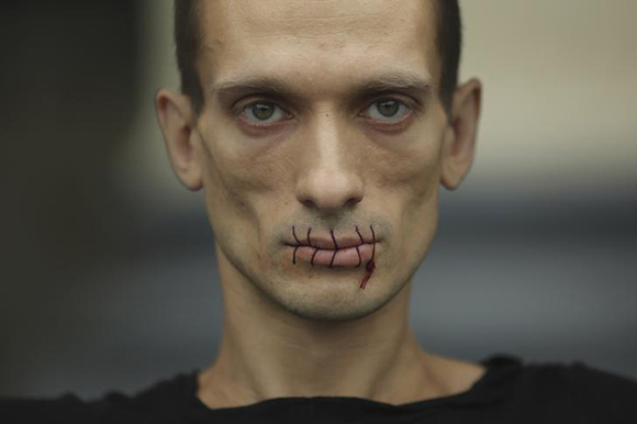 Artist Pyotr Pavlensky, a supporter of jailed members of female punk band "Pussy Riot", looks on with his mouth sewed up as he protests outside the Kazan Cathedral in St. Petersburg, July 23, 2012. A court on Monday rejected a request to call President Vladimir Putin and the head of the Russian Orthodox Church to testify in the trial of three female punk rockers who derided Putin in a protest in the country's main cathedral, their lawyer said. Picture taken July 23, 2012. REUTERS/Trend Photo Agency/Handout (RUSSIA - Tags: CIVIL UNREST CRIME LAW SOCIETY RELIGION POLITICS TPX IMAGES OF THE DAY) FOR EDITORIAL USE ONLY. NOT FOR SALE FOR MARKETING OR ADVERTISING CAMPAIGNS. THIS IMAGE HAS BEEN SUPPLIED BY A THIRD PARTY. IT IS DISTRIBUTED, EXACTLY AS RECEIVED BY REUTERS, AS A SERVICE TO CLIENTS