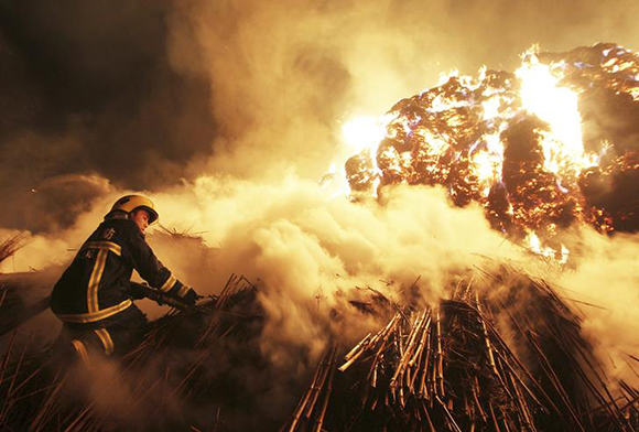 A firefighter attempts to extinguish a fire which broke out on piles of reed at a paper factory in Changde, Hunan province February 16, 2014. No casualty was reported, according to local media. Picture taken February 16, 2014. REUTERS/Stringer (CHINA - Tags: DISASTER SOCIETY TPX IMAGES OF THE DAY) CHINA OUT. NO COMMERCIAL OR EDITORIAL SALES IN CHINA