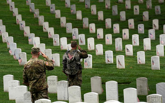 Soldiers from the 3rd U.S. Infantry Regiment (Old Guard) salute as Taps is heard nearby during "Flags-in", where a flag is placed at each of the 284,000 headstones at Arlington National Cemetery, ahead of Memorial Day, in Arlington, Virginia, U.S., May 25, 2017. REUTERS/Kevin Lamarque