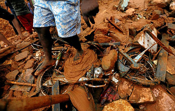 A man stands on top of a damaged bike during a rescue mission at the site of a landslide in Bellana village in Kalutara, Sri Lanka May 26, 2017. REUTERS/Dinuka Liyanawatte TPX IMAGES OF THE DAY