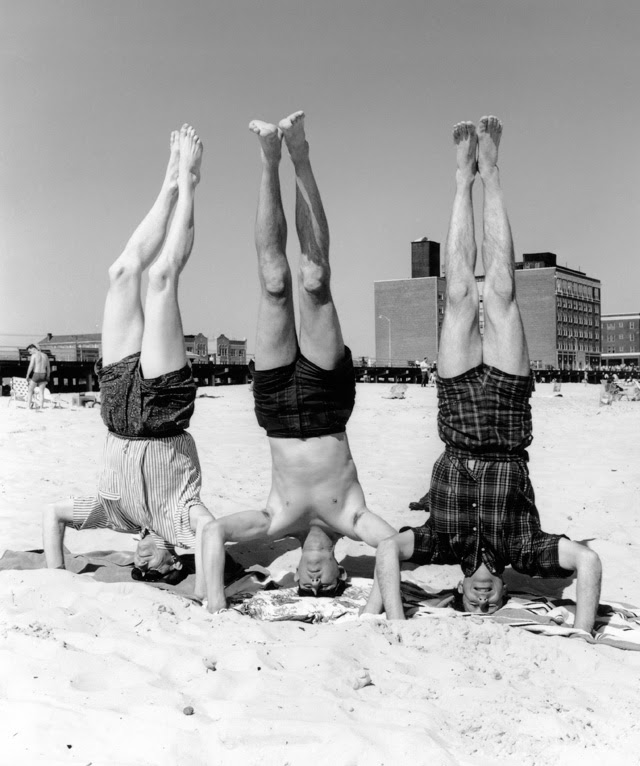 US physicists at Brookhaven Summer School, Brookhaven National Laboratory, New York, USA, 1965. From left to right, the US physicists performing headstands on the beach are: Norton Mark Hintz (1922-2016), Harry Edmund Gove (1922-2009), and Ben Roy Mottelson (born 1926). At the time, Hintz was at the University of Minnesota, Gove was at the University of Rochester, and Mottelson was at the Institute for Theoretical Physics, Copenhagen, Denmark. In this humorous scene, the three physicists are said to be 'spin down state' after lectures, a reference to the quantum property of spin for nuclear particles. Mottelson was awarded a share of the 1975 Nobel Prize in Physics. Photographed in the summer of 1965.