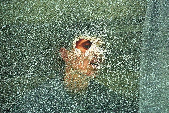 An ethnic Albanian villager looks through a bullet hole in a bus window in the village of Lapusnik 20 km south-west of Kosovo's capital Pristna May 11, 1998. The bus was destroyed during fierce fighting between Serbian forces and ethnic Albanian separatists over the weekend. REUTERS/Yannis Behrakis (KOSOVO - Tags: CIVIL UNREST CONFLICT)