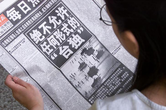 A Chinese woman in Beijing April 9 reads an editorial in a state newspaper which warns Taipei that "Beijing will not allow Taiwan independence in any form." China's state media blasted Taiwan's vice president-elect Annette Lu as a separatist as Beijing cranked up its campaign of invective against the island's newly elected government. Xinhua news agency confirmed that Communist authorities had abandoned their wait-and-see stance towards incoming Chen Shui-bian's administration. The blunt attack against Chen and his independence-leaning Democratic Progressive Party six weeks before its May 20 inauguration ends a moderate stance that had won China international praise since last month's Taiwan elections. A photo of last year's military excercise by Chinese soldiers in Zhejiang province accompanied the article. ASW/PB