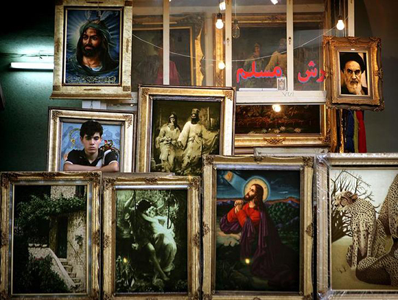An Iranian boy stands behind the paintings he sells inside Tehran's bazaar. Photo by Damir Sagolj
