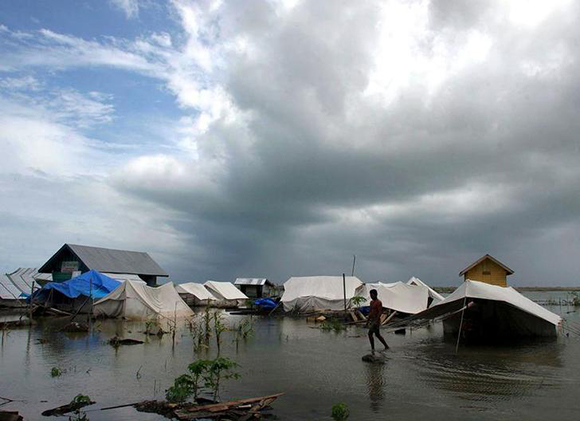 An Acehnese man walks through a flooded area at a refugee camp in the village of Leupung outside the tsunami-hit city of Banda Aceh. Photo by Tarmizy Harva