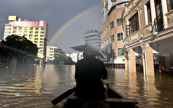 Rainbow appears as Chinese man uses boat to move in flooded street in Wuzhou city, southwest China's Guangxi Zhuang Autonomous Region. Photo by Jason Lee