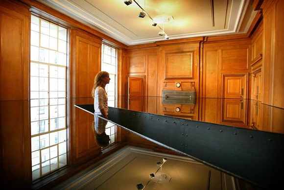 A visitor walks through artist Richard Wilson's sump oil filled room entitled "20:50" on display at the new Saatchi Gallery in London, April 14, 2003. Millionaire Charles Saatchi's new BritArt gallery, which hopes to to attract up to 750,000 visitors a year, is housed on the banks of the River Thames in the ornate and cavernous halls of County Hall, the seat of London's government from 1912 to 1987. The reclusive Saatchi, 59, who made his fortune in advertising with his brother Maurice, has over the past two decades amassed a collection of more than 2,000 pieces and almost single-handedly made the reputations of British artists Damien Hirst and Tracy Emin. PP03040041 REUTERS/Peter Macdiarmid PKM/MD/MA