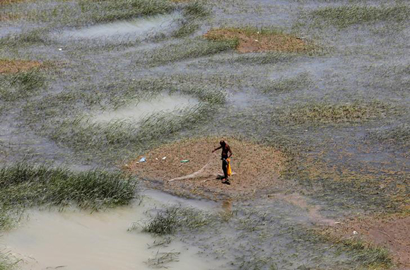 A fisherman stands as he checks his fishing net along the Indus River, Hyderabad, Pakistan June 11, 2017. REUTERS/Akhtar Soomro