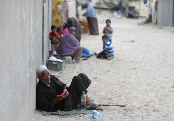 Palestinians sit outside their house in Khan Younis in the southern Gaza Strip June 12, 2017. REUTERS/Ibraheem Abu Mustafa
