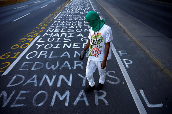 A demonstrator walks on a list of the victims of the violence during protests against Venezuela's president Nicolas Maduro government in Caracas, Venezuela, June 12, 2017. REUTERS/Ivan Alvarado