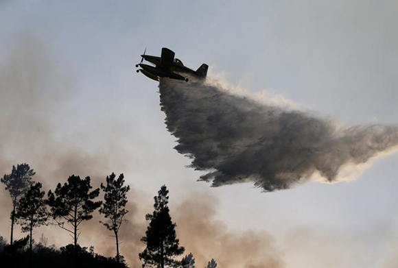 A firefighting plane dumps water on a forest fire in Mendeira, Portugal June 19, 2017. REUTERS/Miguel Vidal TPX IMAGES OF THE DAY