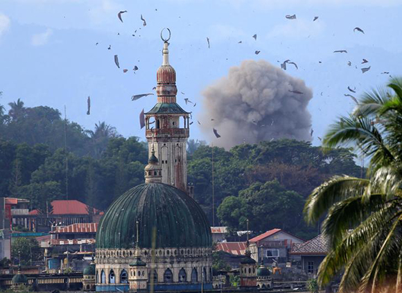 Debris and smoke are seen after an OV-10 Bronco aircraft released a bomb, during an airstrike, as government troops continue their assault against insurgents from the Maute group, who have taken over parts of Marawi city, Philippines June 23, 2017. REUTERS/Romeo Ranoco      TPX IMAGES OF THE DAY