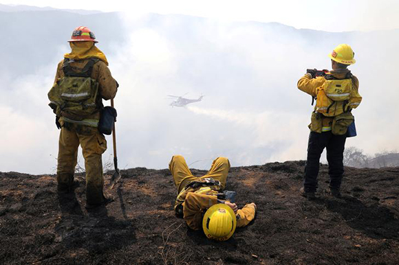 Firefighters watch a helicopter make a water drop on a wildfire burning behind the Getty Center in Mandeville Canyon in Los Angeles, California, U.S., May 28, 2017. REUTERS/Lucy Nicholson TPX IMAGES OF THE DAY