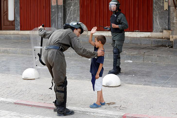 A riot policeman speaks to a boy as protestors demonstrate against alleged corruption in the provincial town of Imzouren, Morocco, June 2, 2017. REUTERS/Youssef Boudlal