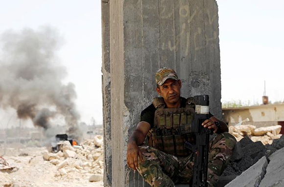 A member of Iraqi military forces rests behind a pillar of a destroyed building, in western Mosul, Iraq June 5, 2017. REUTERS/Erik De Castro TPX IMAGES OF THE DAY
