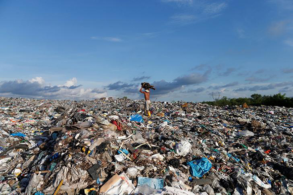A man carries fire-wood as he walks on the top of the huge dump outside Yangon, Myanmar June 6, 2017. REUTERS/Soe Zeya Tun