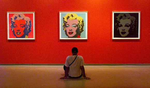 A visitor to the Museum of Contemporary Art sits on the ground listening to an audio guide whilst looking at some of the 1967 Marilyn Monroe screenprints on paper from the exhibition 'The Warhol Look/Glamour Style Fashion' in Sydney December 29. The exhibition features works made during each period of the famous American artist Andy Warhol's career, from sketches and snapshots to major paintings, as well as film and video. ??ª