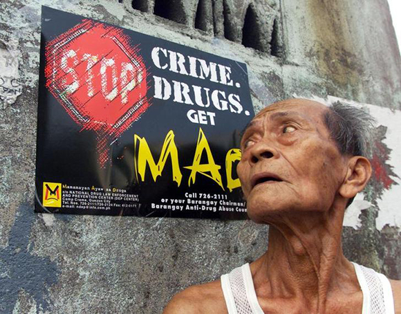 A Filipino elder eyes a poster advertising the government's campaign against drugs in Manila January 17. Newly appointed Interior and [Local Secretary Alfredo Lim] on Monday spraypainted houses of persons convicted or charged as drug pushers. [Lim], a former mayor and police General known for his "Dirty Harry" approach to crime, said the spray paint campaign was the key to removing the drug menace in the country.