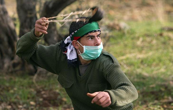 A Palestinian protester uses a sling to throw stones at Israeli security forces during clashes at a protest against the controversial Israeli barrier in the West Bank village of Bilin near Ramallah December 31, 2010. REUTERS/Darren Whiteside (WEST BANK - Tags: CIVIL UNREST MILITARY)