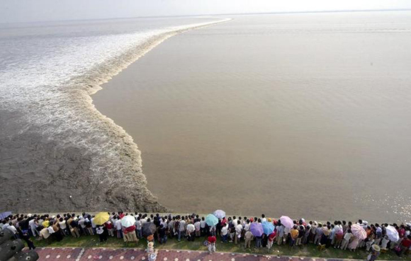 Chinese tourists gather to watch the soaring tide on the bank of Qiantang River in Haining, east China's Zhejiang province. Photo by China Newsphoto