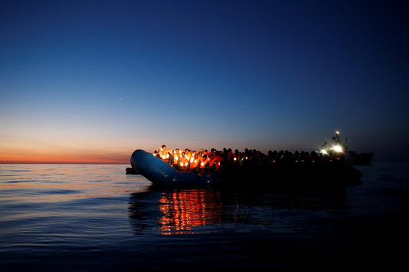 Migrants on a rubber dinghy await rescue by the Malta-based NGO Migrant Offshore Aid Station (MOAS). Photo by Darrin Zammit Lupi