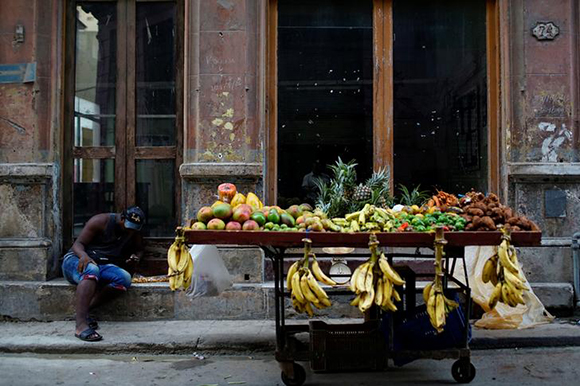 A street vendor checks his mobile as he waits for clients in downtown Havana, Cuba. Photo by Alexandre Meneghini