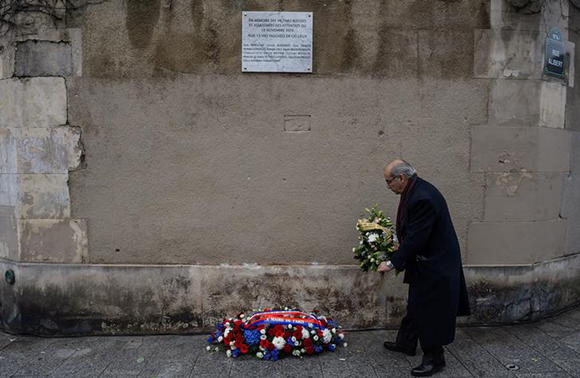 A man pays respects under a commemorative plaque unveiled by French President Francois Hollande and Paris Mayor Anne Hidalgo next to the "Le Carillon" and "Le Petit Cambodge" bars and restaurants, in Paris, France. Photo by Christophe Petit Tesson/Pool