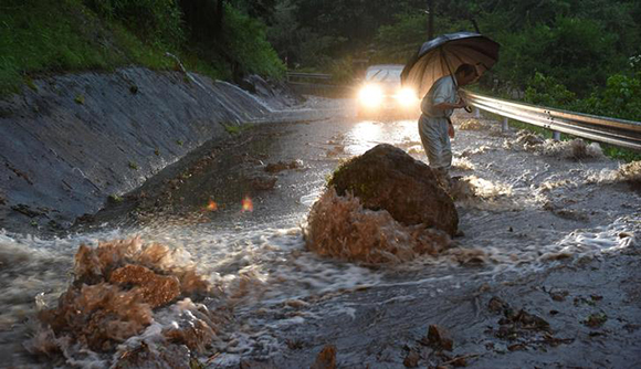 A flooded road with fallen rocks is pictured in Hita in Oita Prefecture, Japan, after torrential rain hits, in this photo taken by Kyodo. Photo by Kyodo