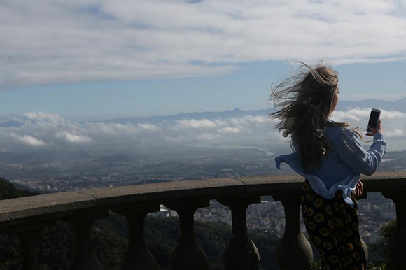 A woman looks at her cell phone at the Corcovado mountain in Rio de Janeiro, Brazil. Photo by Pilar Olivares