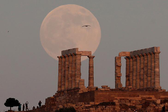 A fullmoon rises over the Temple of Poseidon, the ancient Greek god of the seas, in Cape Sounion, east of Athens, Greece, July 8, 2017. Photo by Costas Baltas