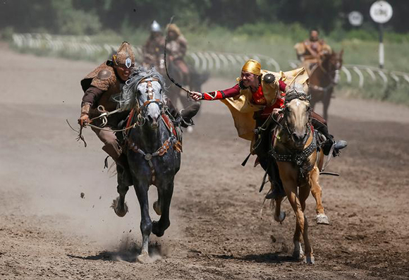 Riders of Nomad Stunts group perform the Kyz Kuu (catch the girl) national riding game, where a girl whips a male contestant as she defends herself, during a show in Almaty, Kazakhstan July 9, 2017. Photo by Shamil Zhumatov