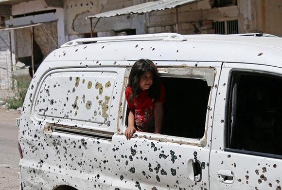 A girl looks out from a bullet-riddled bus in a rebel-held part of the southern city of Deraa, Syria July 9, 2017. Photo by Alaa Al-Faqir