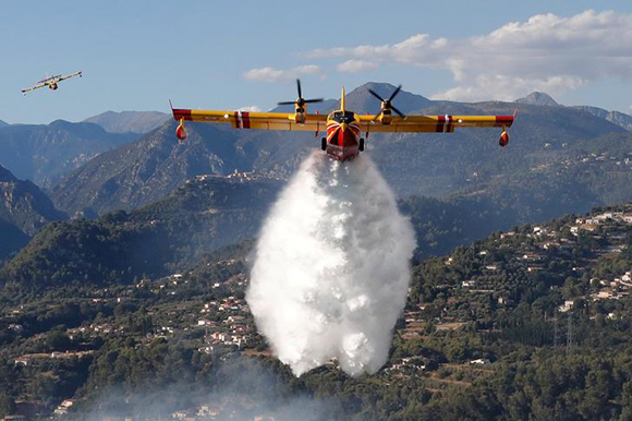  A Canadair firefighting aircraft drops water on a wildfire which burns a forest in Carros, near Nice, France, July 24, 2017. Photo by Eric Gaillard