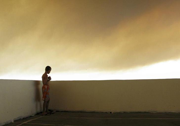  A young tourist watches a forest fire from a balcony in his hotel at Kiotari village on the island of Rhodes. Photo by Rafal Klimkiewicz REUTERS/Rafal Klimkiewicz/EDYTOR (GREECE)