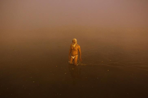 A Sadhu or a Hindu holy man walks after taking a holy bath at Sangam, the confluence of the Ganges, Yamuna and Saraswati rivers, on a foggy winter morning, on the occasion of Makar Sankranti festival in the northern Indian city of Allahabad. Photo by Jitendra Prakash