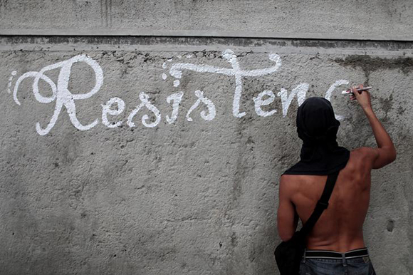 An opposition supporter paints the word "resistance" on a wall while rallying against Venezuela's President Nicolas Maduro's government in Caracas, Venezuela August 4, 2017. Photo by Marco Bello