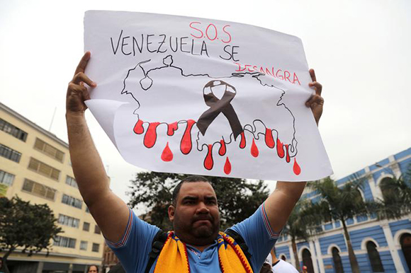 A demonstrator holds a sign that reads "S.O.S Venezuela is Bleeding" at a protest against Venezuela's President Nicolas Maduro's government, August 8, 2017. Photo by Guadalupe Pardo