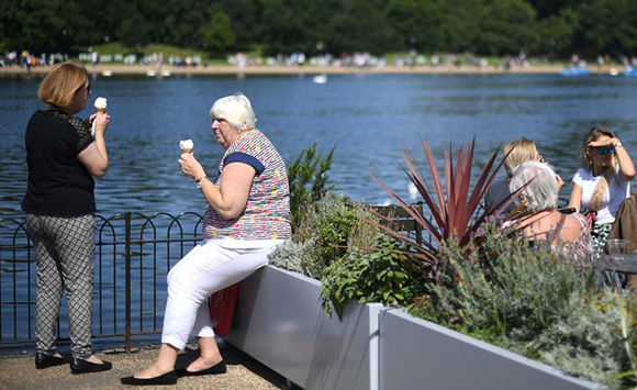 Women eat ice cream as they overlook the Serpentine, on a sunny day in Hyde Park, London, Britain August 13, 2017. Photo by Hannah McKay