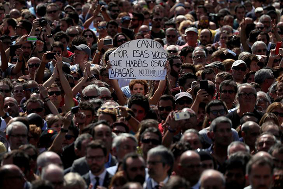 A woman holds a sign that reads "I sing today for those voices that you have dared to shut up. We are not afraid" while observing a minute of silence at Placa de Catalunya, a day after a van crashed into pedestrians at Las Ramblas in Barcelona, Spain August 18, 2017. Photo by Susana Vera