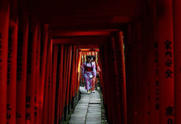 Women dressed in yukata, or a casual summer kimonos, walk through red-coloured wooden torii gates at the Nezu shrine in Tokyo, Japan August 22, 2017. Photo by Kim Kyung-Hoon