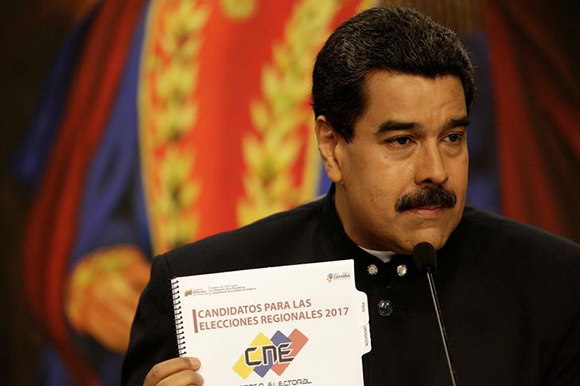 Venezuela's President Nicolas Maduro shows a book that reads "Candidates for 2017 regional elections" during a news conference at Miraflores Palace in Caracas, Venezuela August 22, 2017. Photo by Marco Bello