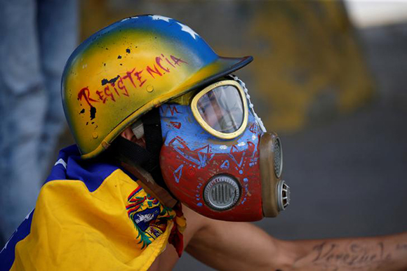A demonstrator looks on while clashing with riot security forces during a rally against Venezuela's President Nicolas Maduro's government in Caracas, Venezuela. Photo by Andres Martinez Casares.