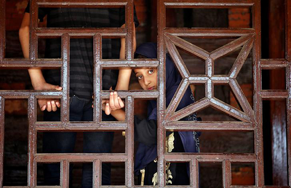 A Muslim girl looks on behind a wooden window frame at the shrine of Mir Syed Ali Hamdani, a Sufi saint, during an annual religious festival in Srinagar. Photo by Danish Ismail